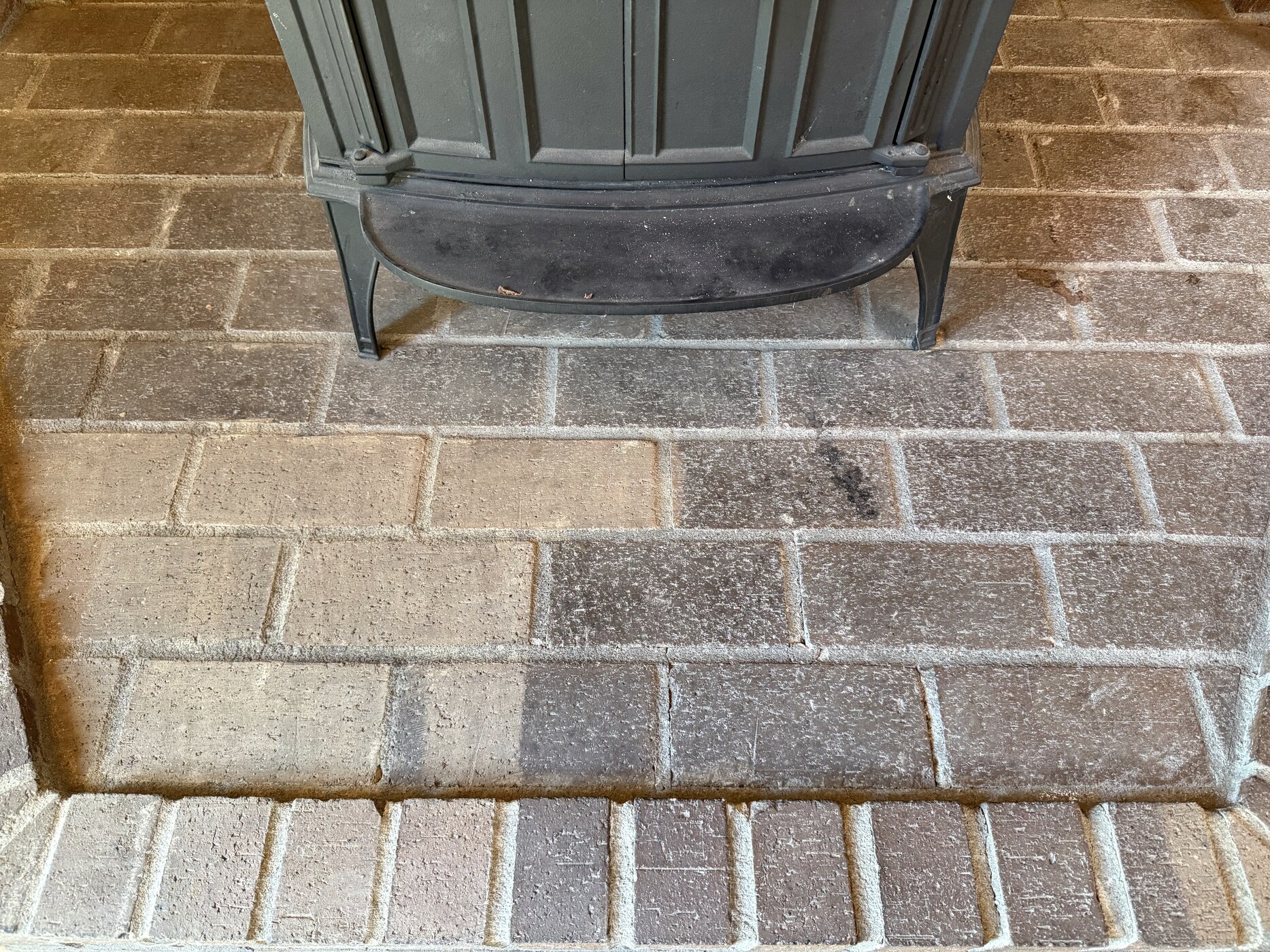 Brick fireplace hearth — sooty brick on the left, clean brick after laser cleaning on the right